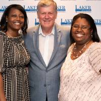 2 women pose for picture at photo station with tom